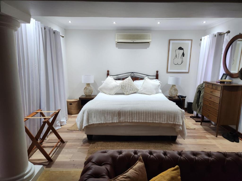 a bedroom with a bed and a couch at Aleia Cottage in Pretoria