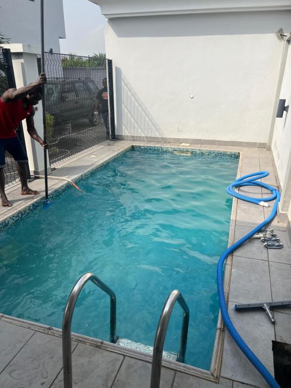 a pool of blue water with a man standing next to it at Lekki shared apartment in Lekki