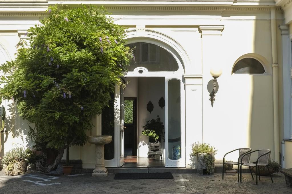un ingresso a un edificio bianco con un albero di B&B Villa Ocsia a San Giorgio a Cremano