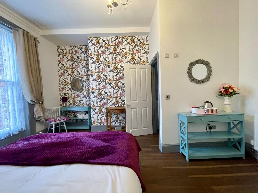 een slaapkamer met een paars bed en een spiegel bij LilyRose Hotel in Whitby