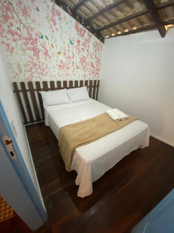 ein Schlafzimmer mit einem weißen Bett und einer Blumenwand in der Unterkunft Apartamento Charme Guará in Guaramiranga