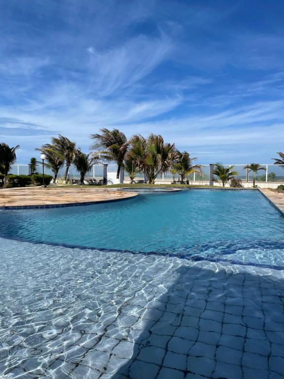 een zwembad met palmbomen op de achtergrond bij Apartamento de Frente para o Mar na praia da Taiba Ceará in Taíba