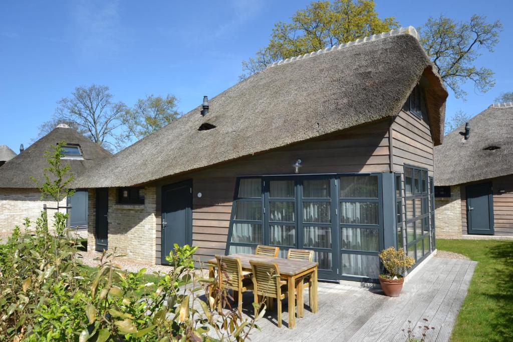 a house with a thatched roof with a table and chairs at Dormio Park Scorleduyn in Schoorl