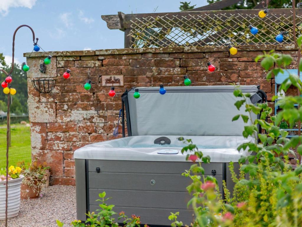 a hot tub in a garden with a brick wall at 1 Bed in Eden Valley 82493 in Kirkoswald