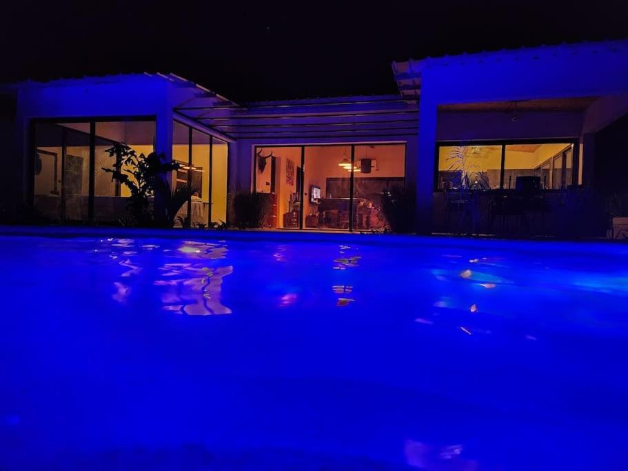 Ndangane的住宿－Tiny Villa Votre Villa Privatisée，享有蓝色灯光的房子的夜景