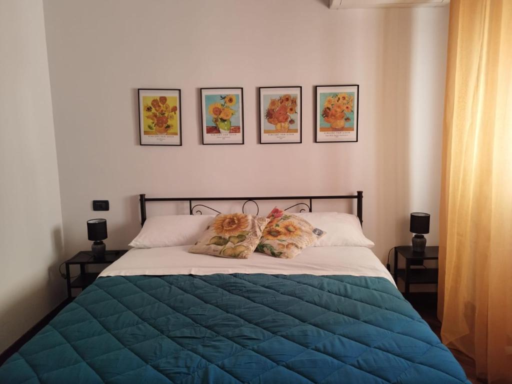 ein Bett mit blauer Decke und drei Bildern an der Wand in der Unterkunft I GIRASOLI Short Rent in Palermo