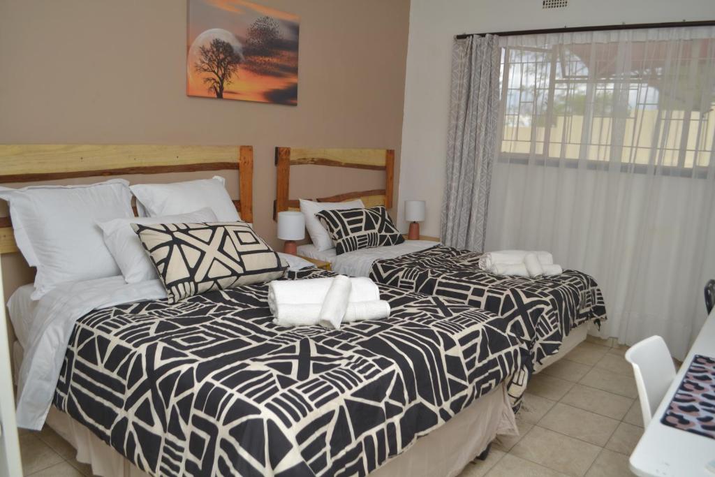 two beds with black and white comforters in a bedroom at Wanjara's Nest in Windhoek