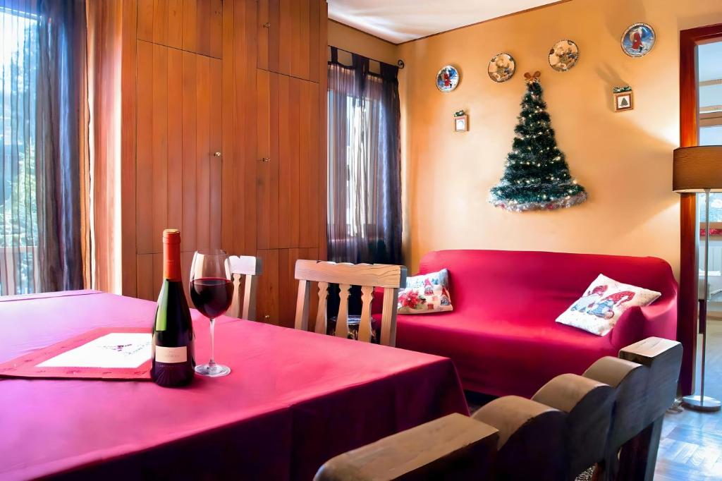 a red table with a bottle of wine and a christmas tree at Lo Scoiattol House in Limone Piemonte