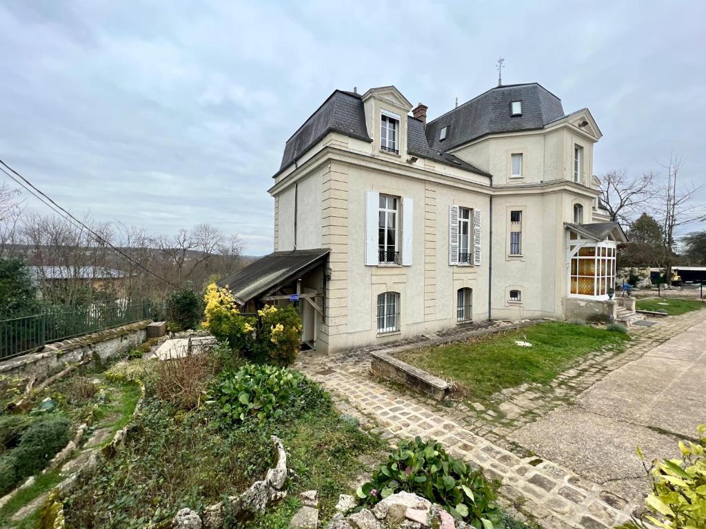 een groot wit huis met een zwart dak bij Une nuit royale / Proche Forêt in Veneux-les-Sablons