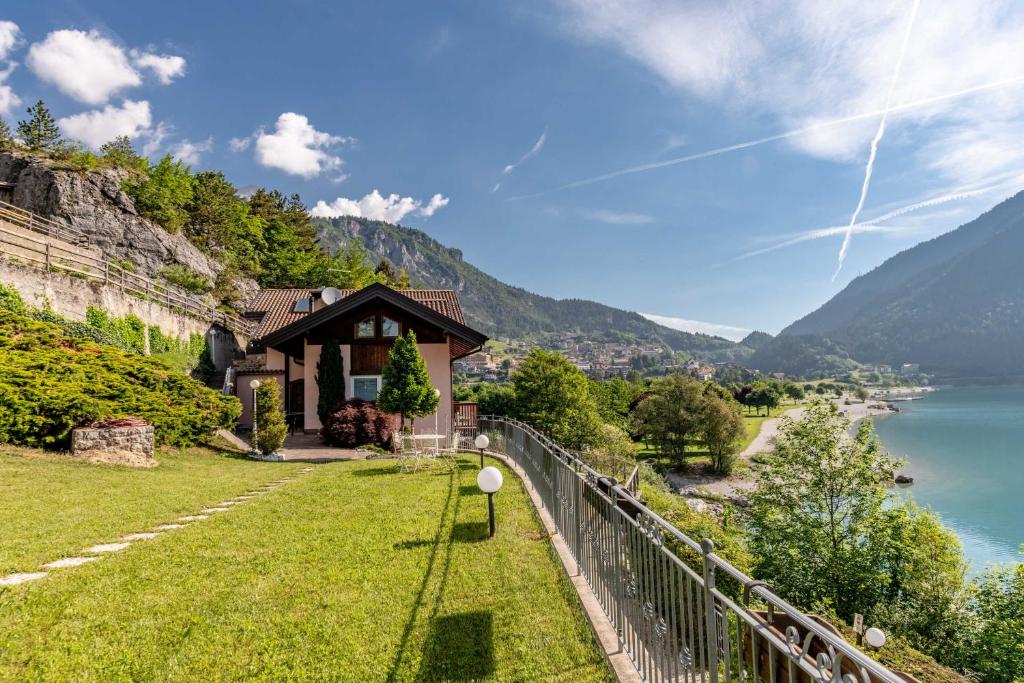 ein Haus auf einem Hügel neben einem Wasserkörper in der Unterkunft Lo scrigno del lago Molveno Trento in Molveno