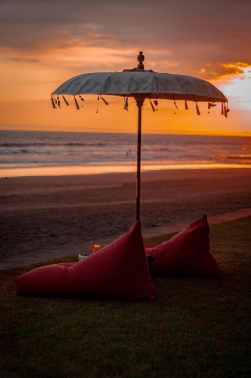 a umbrella on the beach with a sunset in the background at Kelapa Retreat & Spa in Pulukan