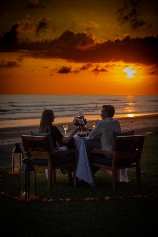 a couple sitting at a table on the beach at sunset at Kelapa Retreat & Spa in Pulukan