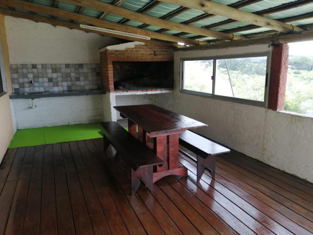 Habitación con banco, mesa y ventana en Cabaña Jacarandá, en Villa Serrana