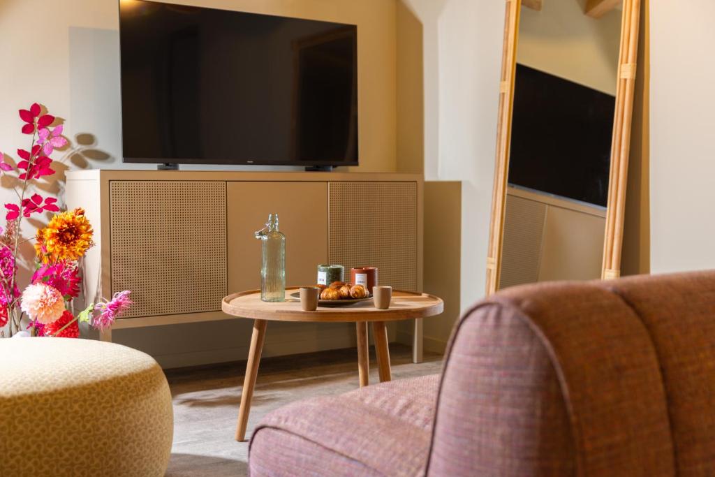 a living room with a table and a tv at La Villa Serra - Appartements in Agen