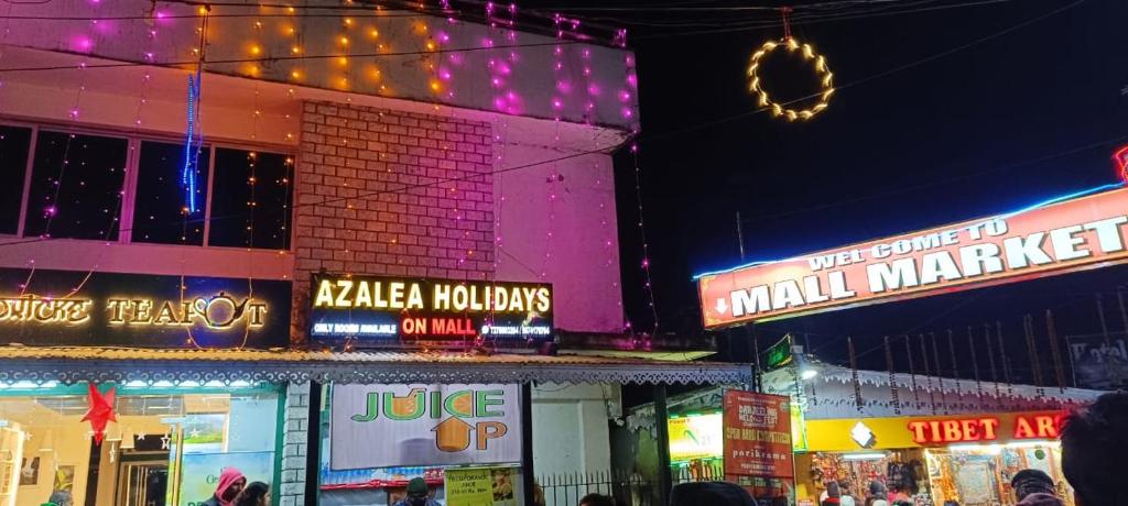 un groupe de bâtiments avec des panneaux de néons la nuit dans l'établissement Azalea Holidays On Mall, à Darjeeling