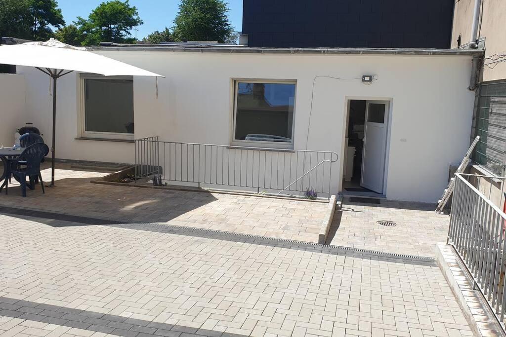 a white house with a table and an umbrella at Ferienwohnung in Bochum