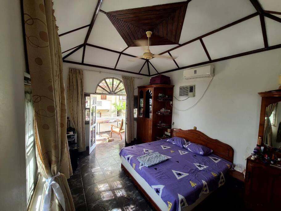 una camera da letto con letto con lenzuola viola e soffitto di Sarojeni Apartments a Negombo