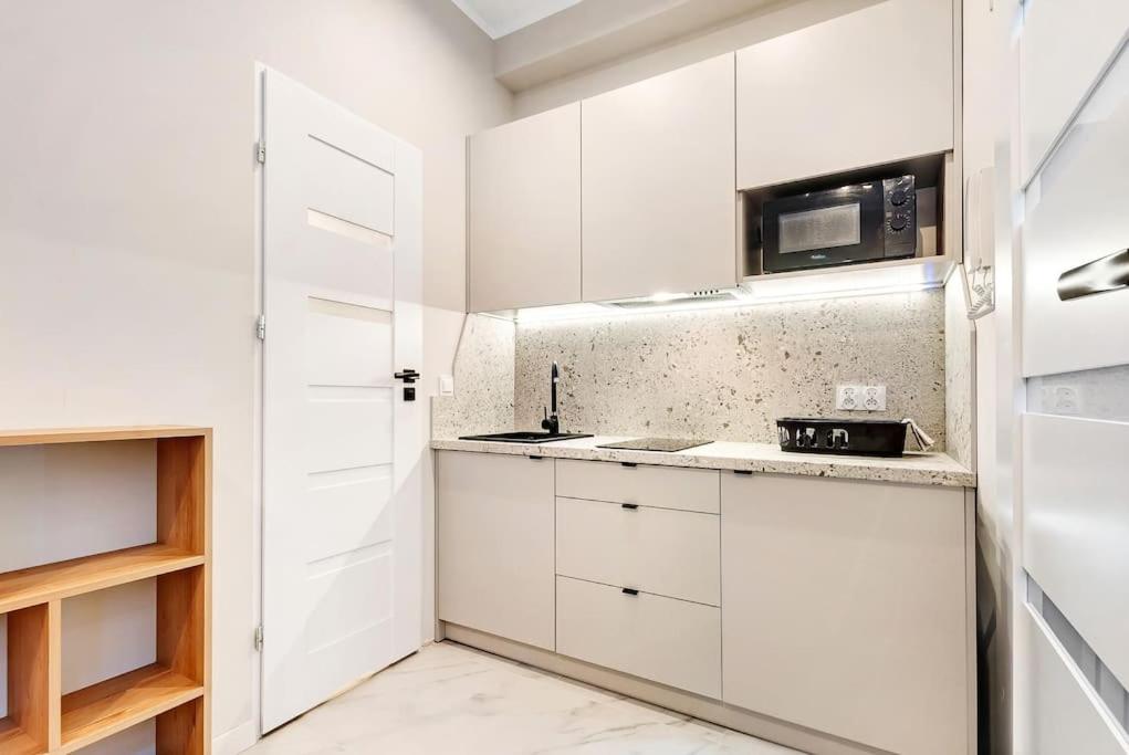 a white kitchen with white cabinets and a microwave at Tiny and cosy studio only 4 you in Katowice