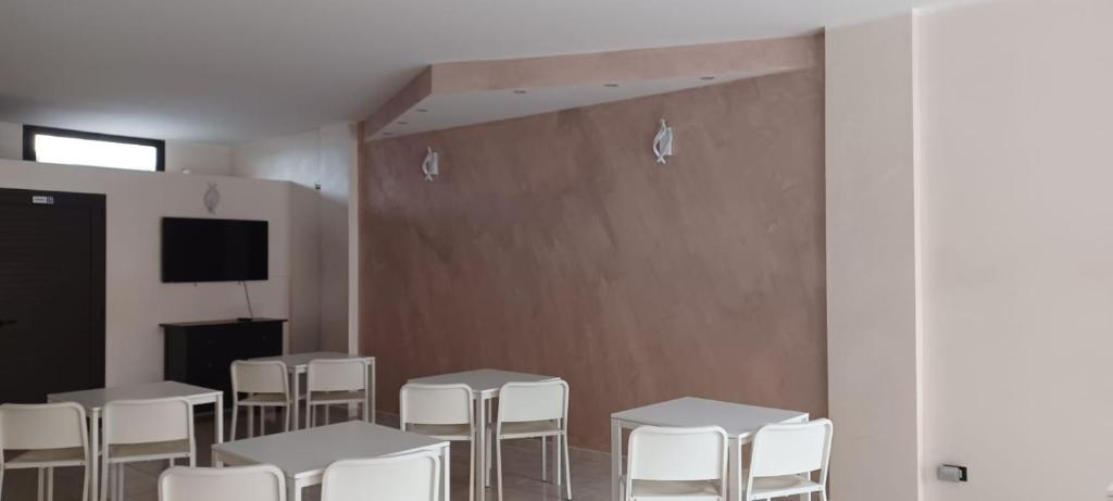 レージナにあるAFFITTACAMERE Da Roccoの白いテーブルと椅子、テレビが備わる客室です。