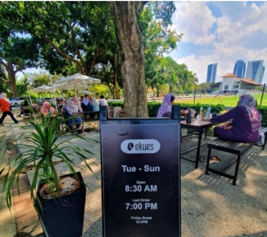 a sign in a park with people sitting at tables at Jannah Guest House Putrajaya in Putrajaya