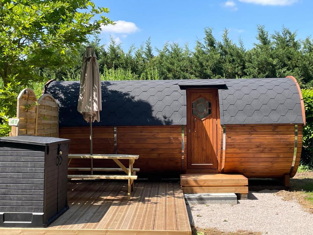 una sauna de madera con sombrilla y banco en TONNEAU HERBERGEMENT INSOLITE AU CAMPING DES NIERES en Ébreuil