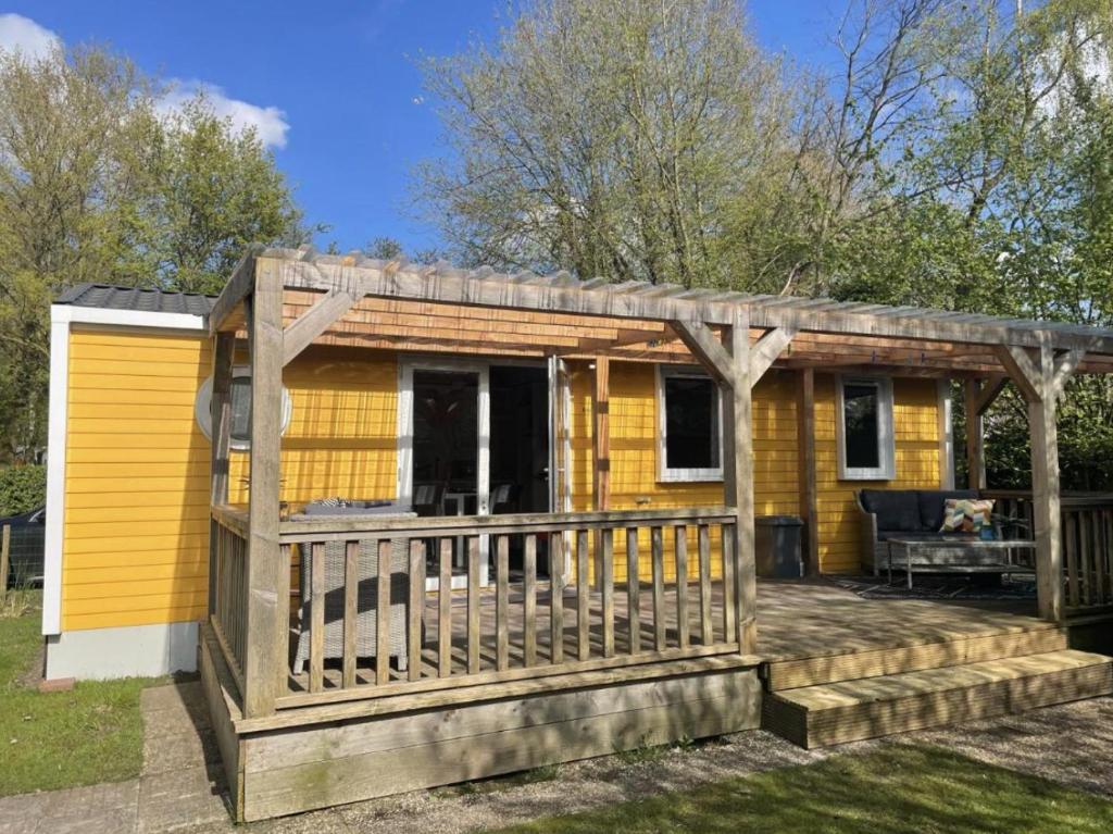 uma pequena casa amarela com um deque em Ruime 5-persoons chalet aan het Bergumermeer em Suameer