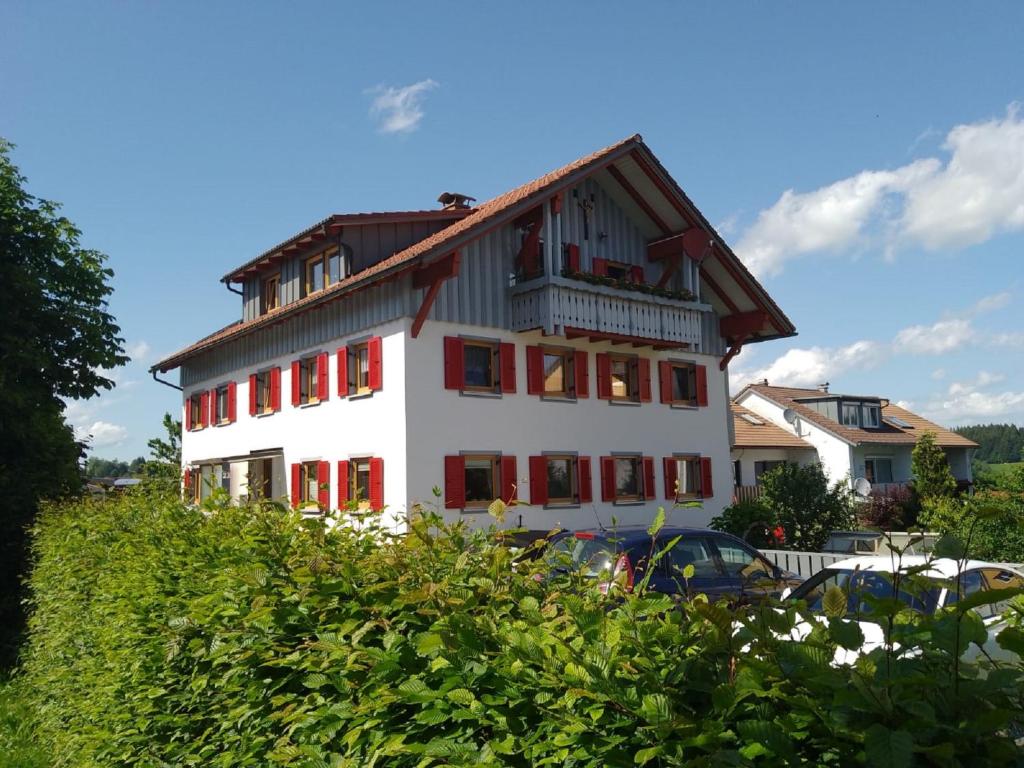 a large white building with red windows and a car at Gästehaus Grath in Lindenberg im Allgäu