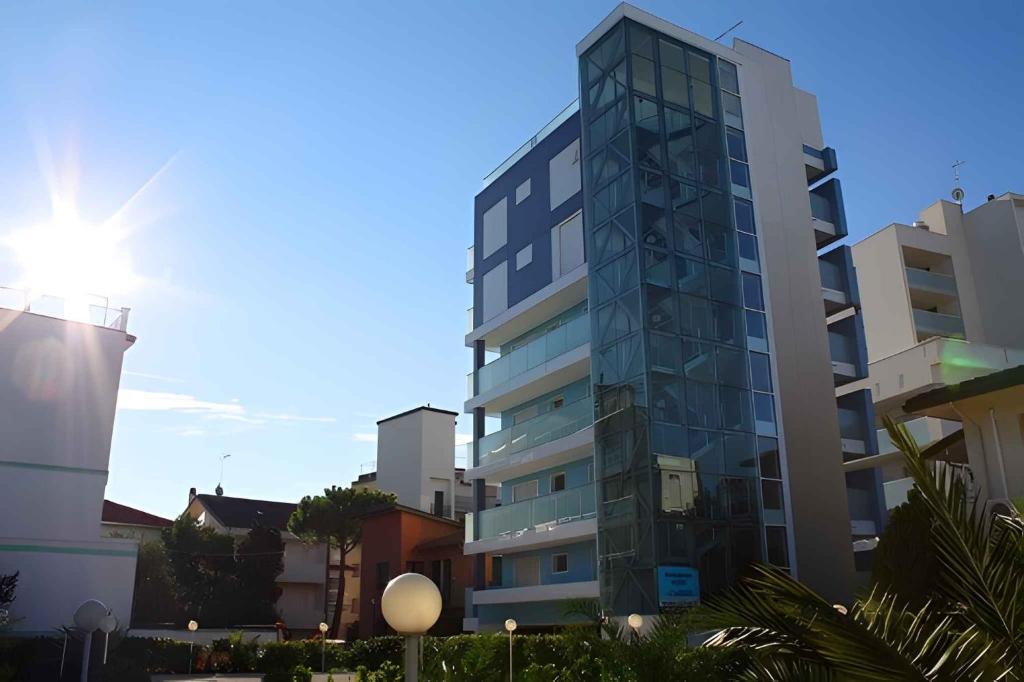 un grand bâtiment en verre avec le soleil derrière lui dans l'établissement Apartment in Lignano Sabbiadoro 21778, à Lignano Sabbiadoro