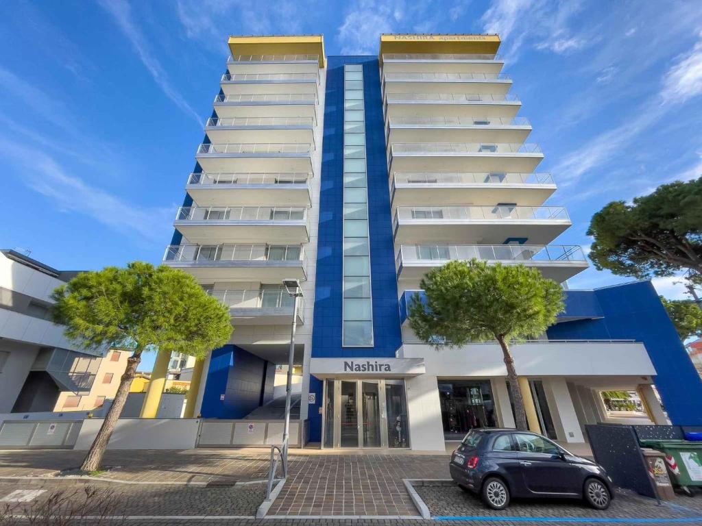 een blauw-wit gebouw met een auto voor de deur bij Apartments in Lignano Sabbiadoro 31391 in Lignano Sabbiadoro