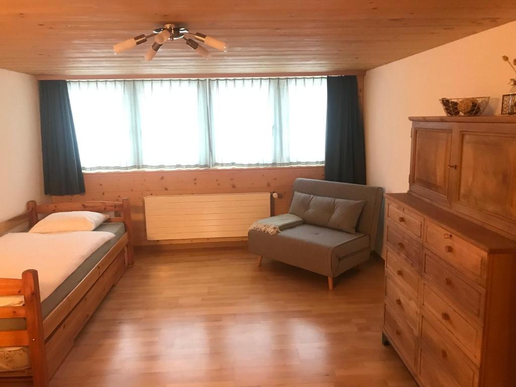 um quarto com uma cama, uma cadeira e janelas em Bijou 2 hübsche 1 Zimmer Wohnung em Herisau