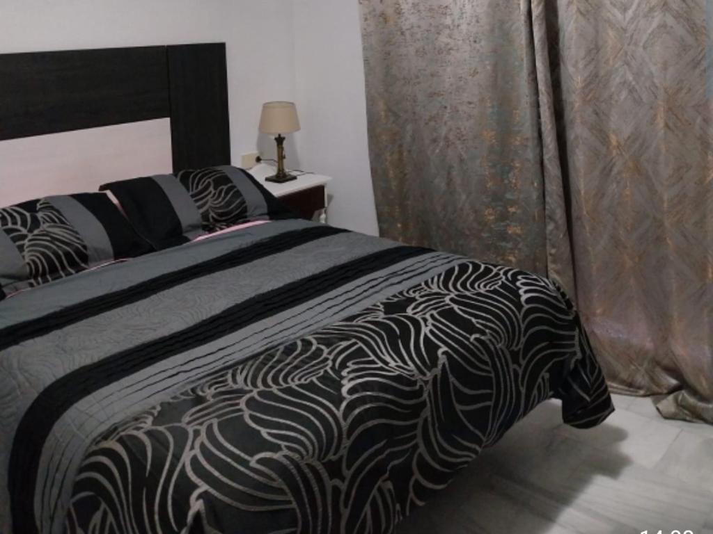 a bedroom with a bed with a black and white comforter at Marbella apartamento en Malaga in Málaga