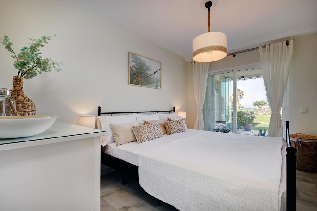 a white bedroom with a large bed and a window at La Cala gorgeous 2 bedroom apartment with stunning gardens, pools and sea views in Mijas Costa