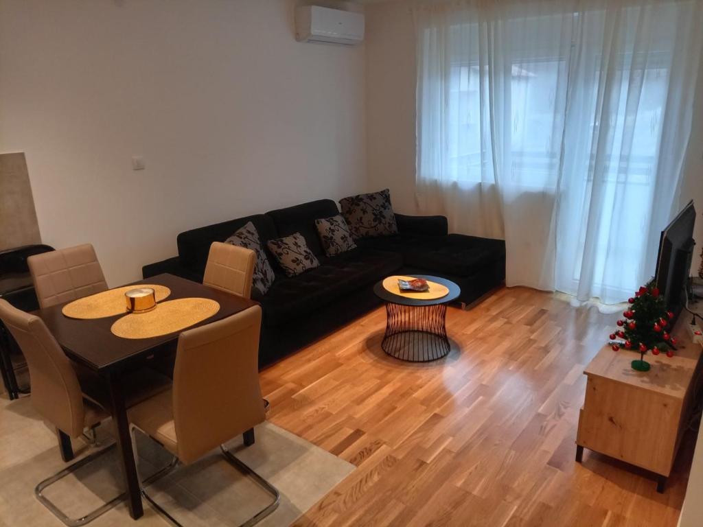 ein Wohnzimmer mit einem schwarzen Sofa und einem Tisch in der Unterkunft Apartman Pan in Sokobanja