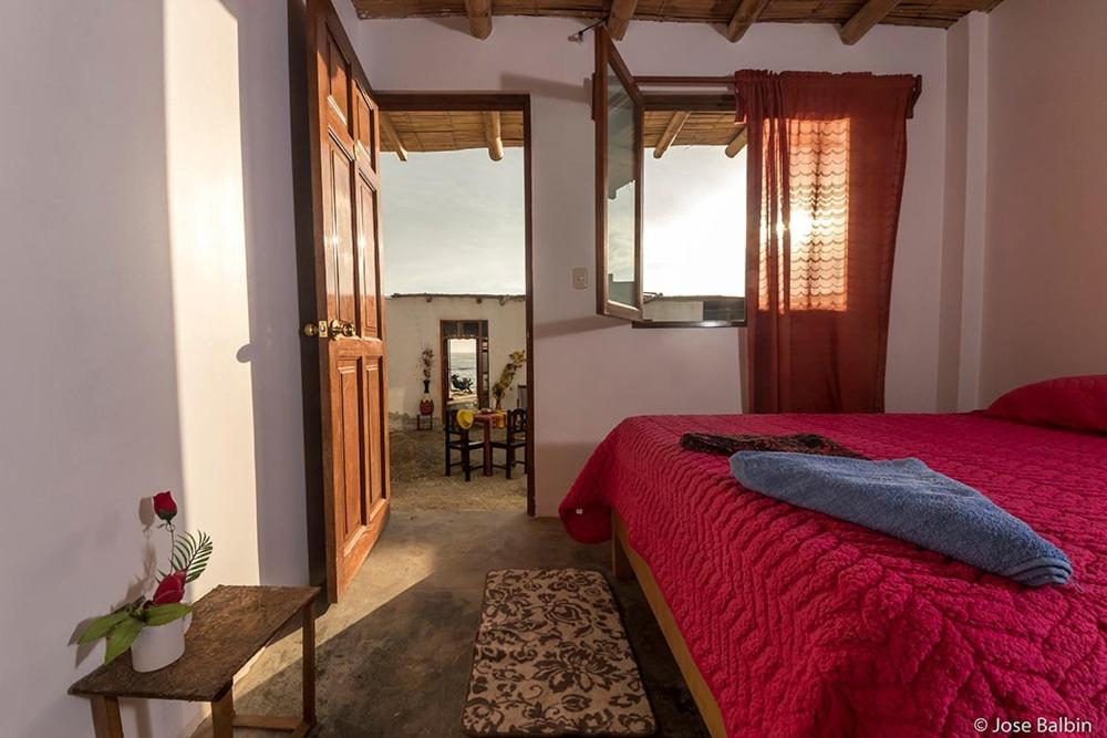 1 dormitorio con cama roja y espejo en El Paraíso, en Huarmey