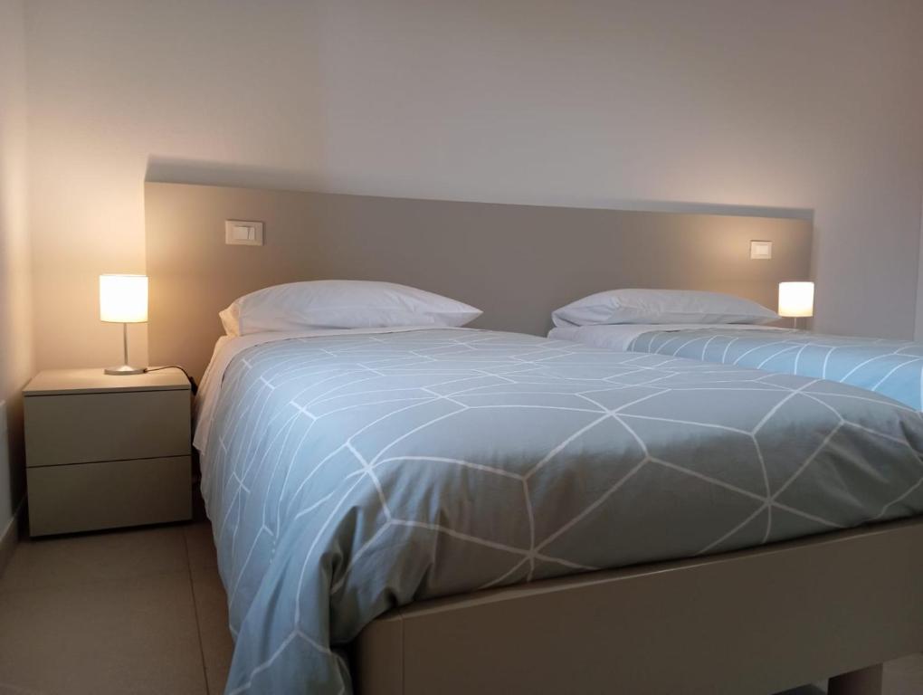 two beds in a bedroom with two lamps on night stands at Maresol apartment in Carrara