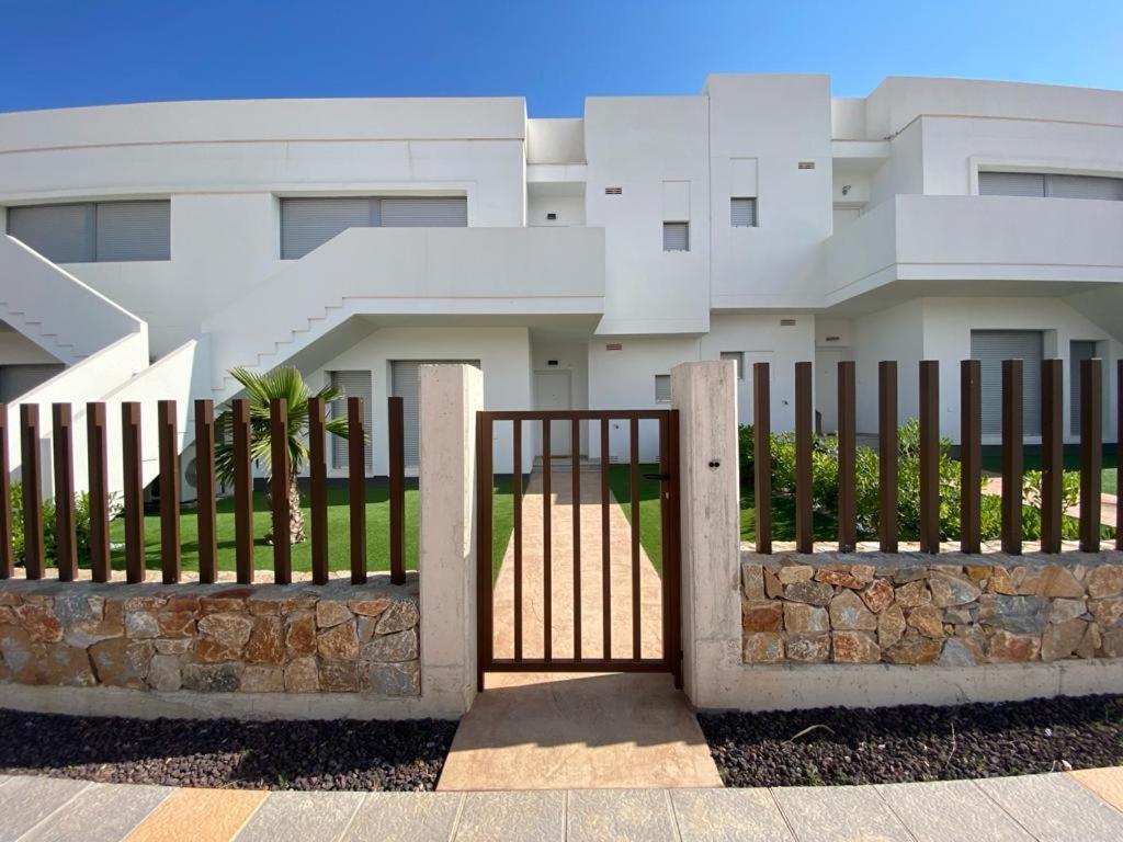 uma cerca em frente a um edifício branco em Premium Holidays - Modern holiday home with pool nearby Vistabella Golf em Orihuela