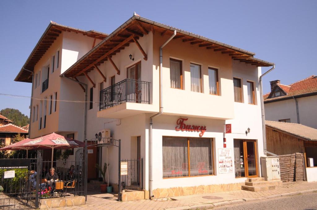 a white building with a sign on it at Family Hotel Biju in Tryavna