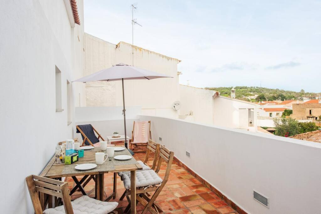 een tafel en stoelen op een balkon met een parasol bij Casa elegante em Vila tranquila in Barão de São Miguel