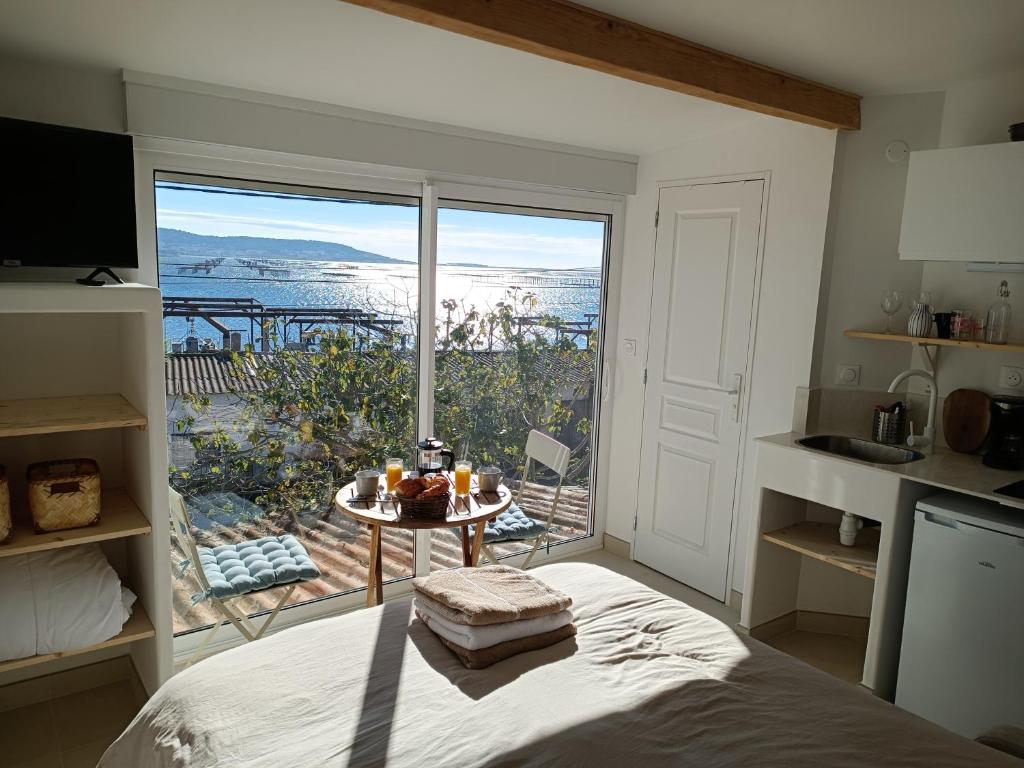 ein Schlafzimmer mit einem Bett und einem großen Fenster in der Unterkunft "La Cabane de Thau" avec vue imprenable sur Sète in Loupian