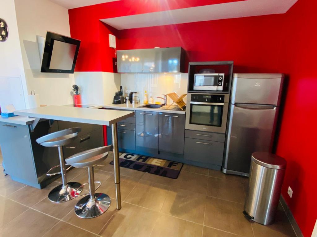 una cocina con paredes rojas y una barra con taburetes en Appartement T2 cosy à Rodez, en Rodez