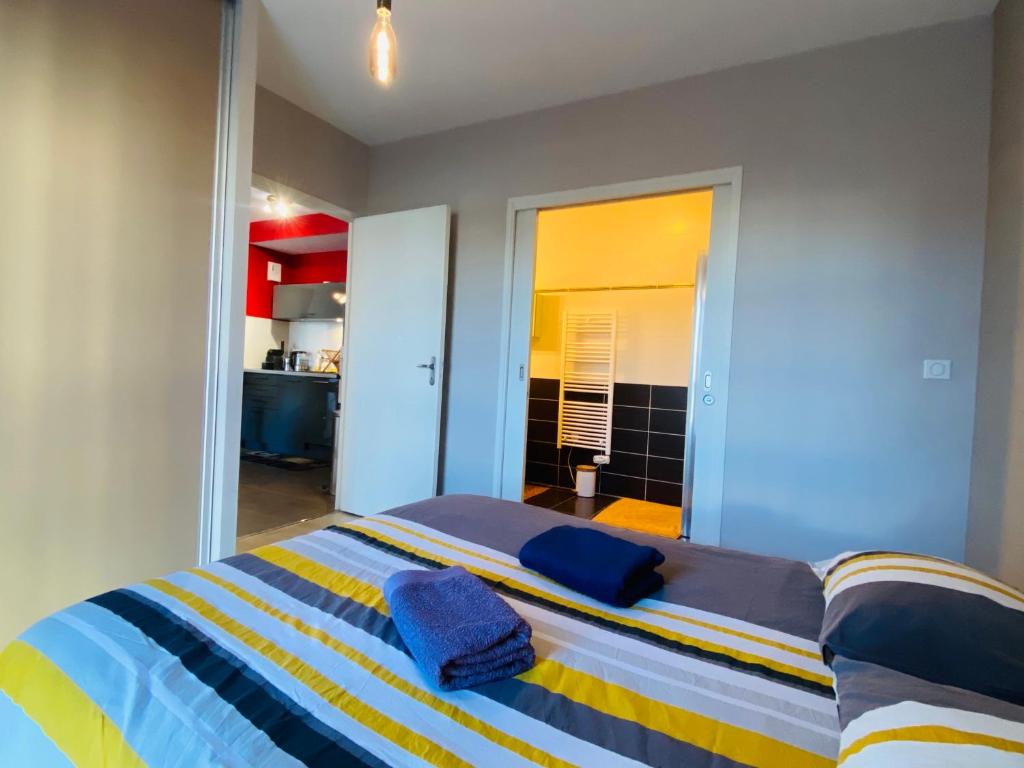 1 dormitorio con 1 cama con rayas azules y amarillas en Appartement T2 cosy à Rodez, en Rodez