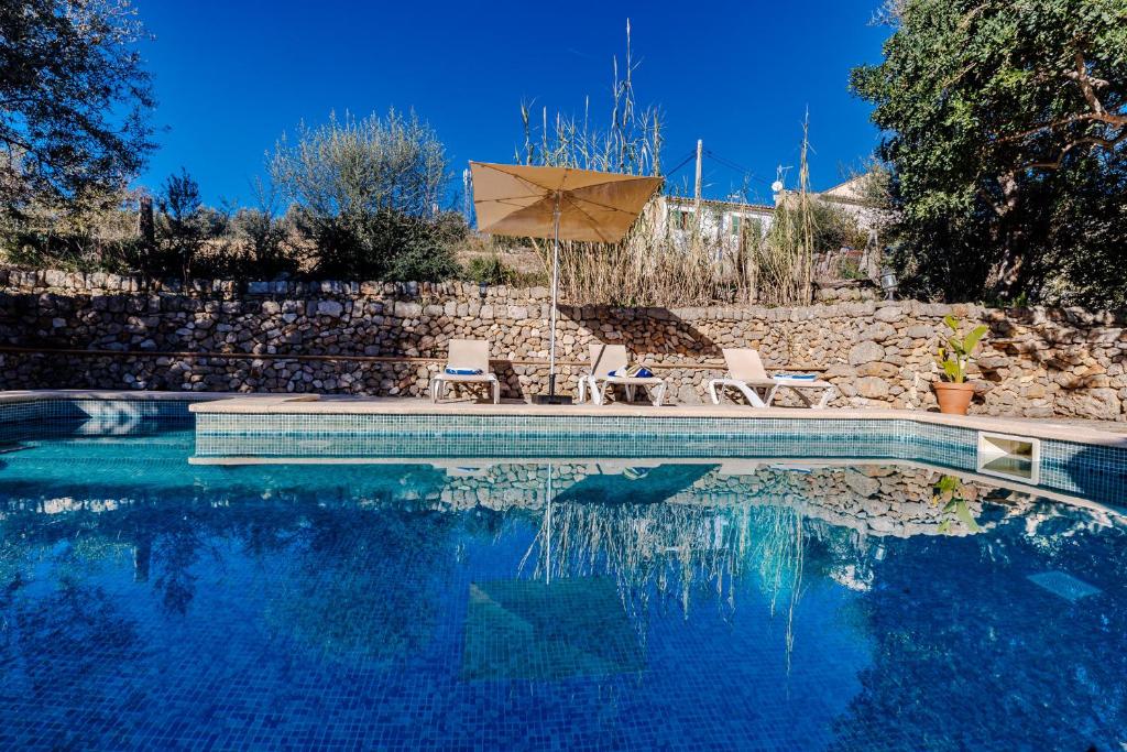 a swimming pool with two chairs and an umbrella at Villa Can Abrines in Lloseta