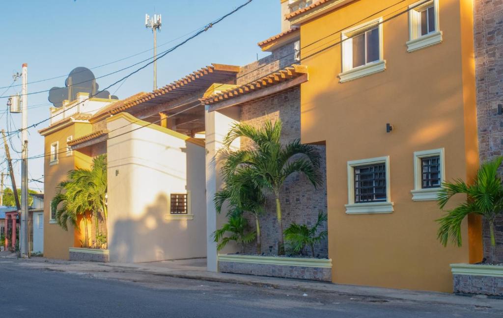 um edifício amarelo com palmeiras numa rua em Diosamar Hotel y Suites em Santo Domingo