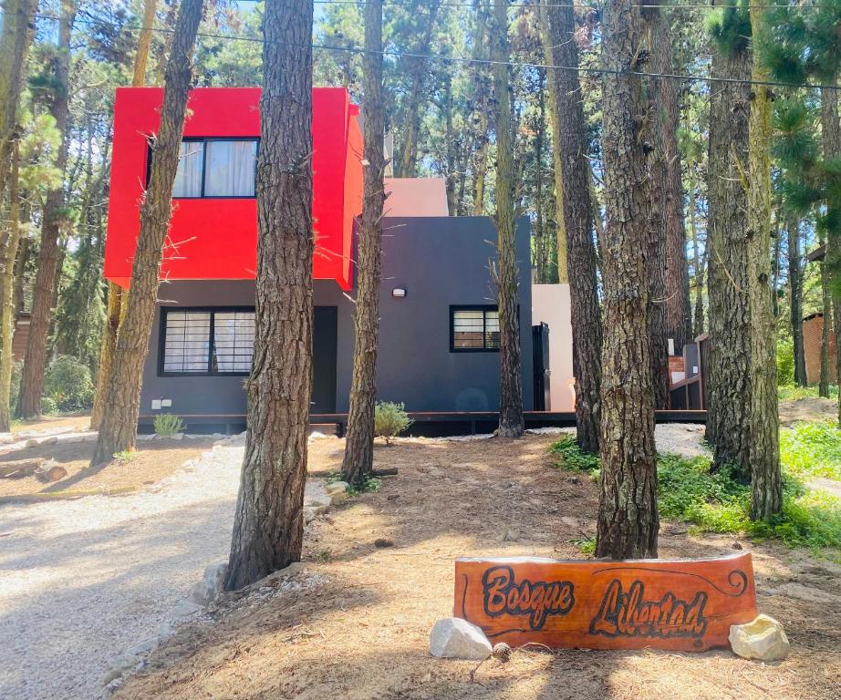 a house in the woods with a sign in front of it at Bosque Libertad Loft in Mar Azul