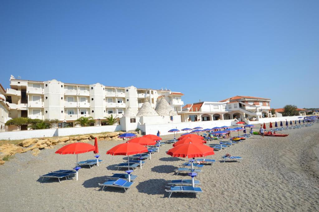 eine Gruppe von Stühlen und Sonnenschirmen am Strand in der Unterkunft Hotel Residence Il Gabbiano in Cirò Marina