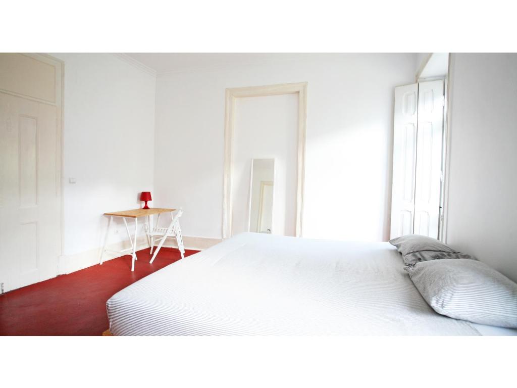 a white bedroom with a bed and a table at Friendly Hills Bairro Alto in Lisbon