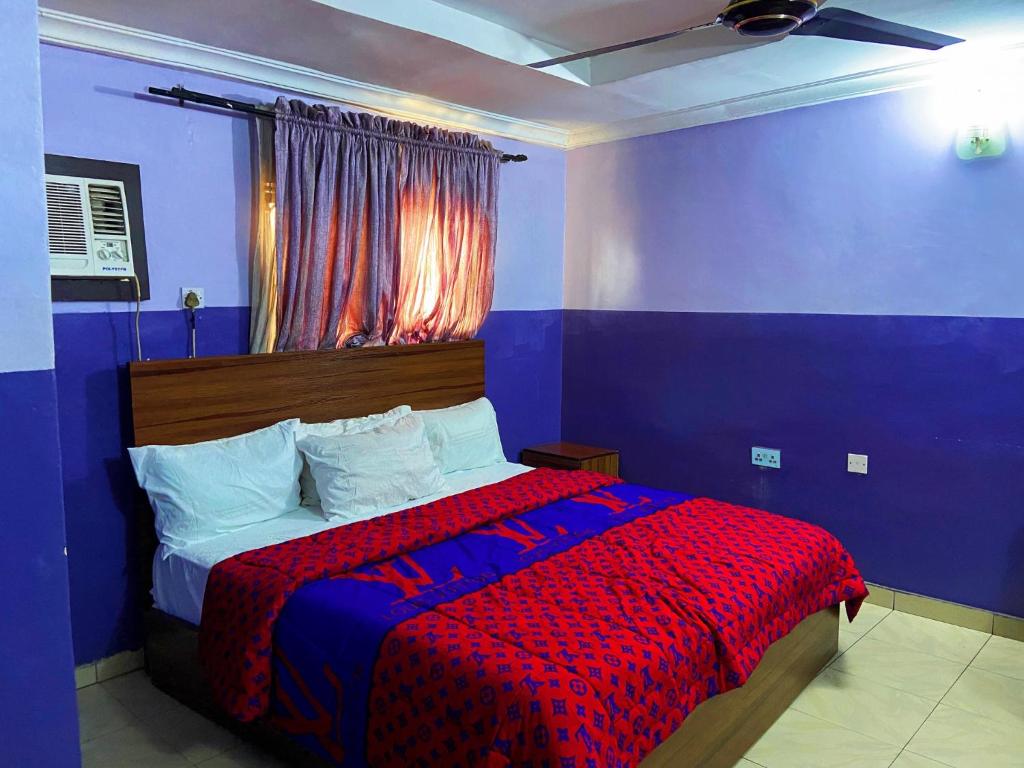 een blauwe slaapkamer met een bed met een rode deken bij Suofega Hotel and Suites in Ughelli