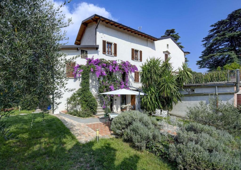 Una casa blanca con flores púrpuras. en Il Nido dei Gufi Bed and Breakfast, en Toscolano Maderno
