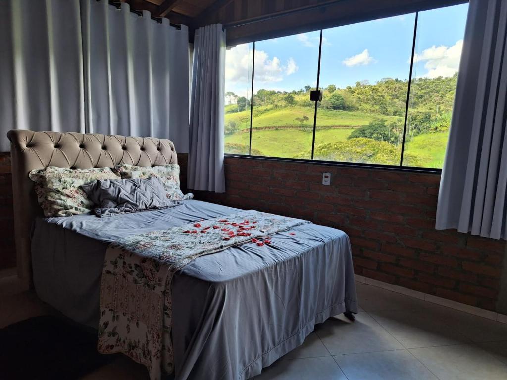 a bed with flowers on it in a room with windows at Aconchego da Beth in Camanducaia