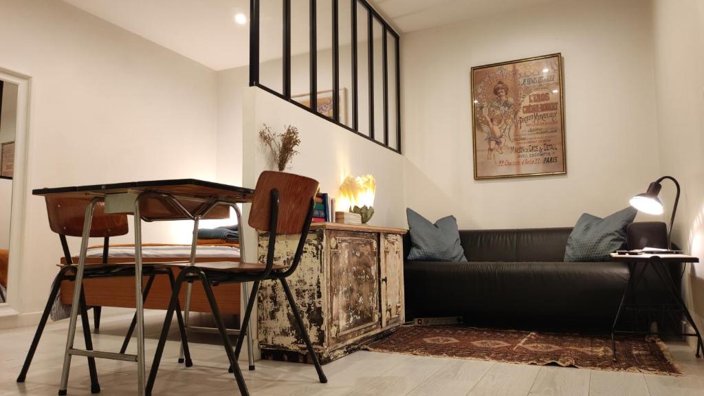 ein Wohnzimmer mit einem Sofa und einem Tisch in der Unterkunft Cosy Studio aux Batignolles - Proche Montmartre in Paris